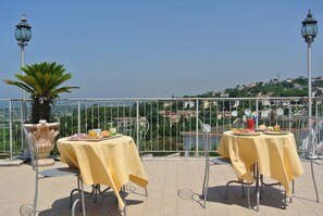Una terraza con dos mesas preparadas para comer, con vistas a un paisaje montañoso.