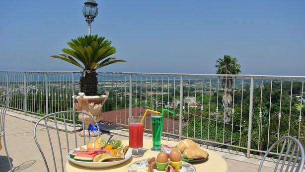 Una mesa con comida y bebidas en un balcón con vistas a un paisaje urbano.