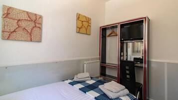 Camera d'albergo con un letto, un armadio, uno specchio e due opere d'arte appese alle pareti.
