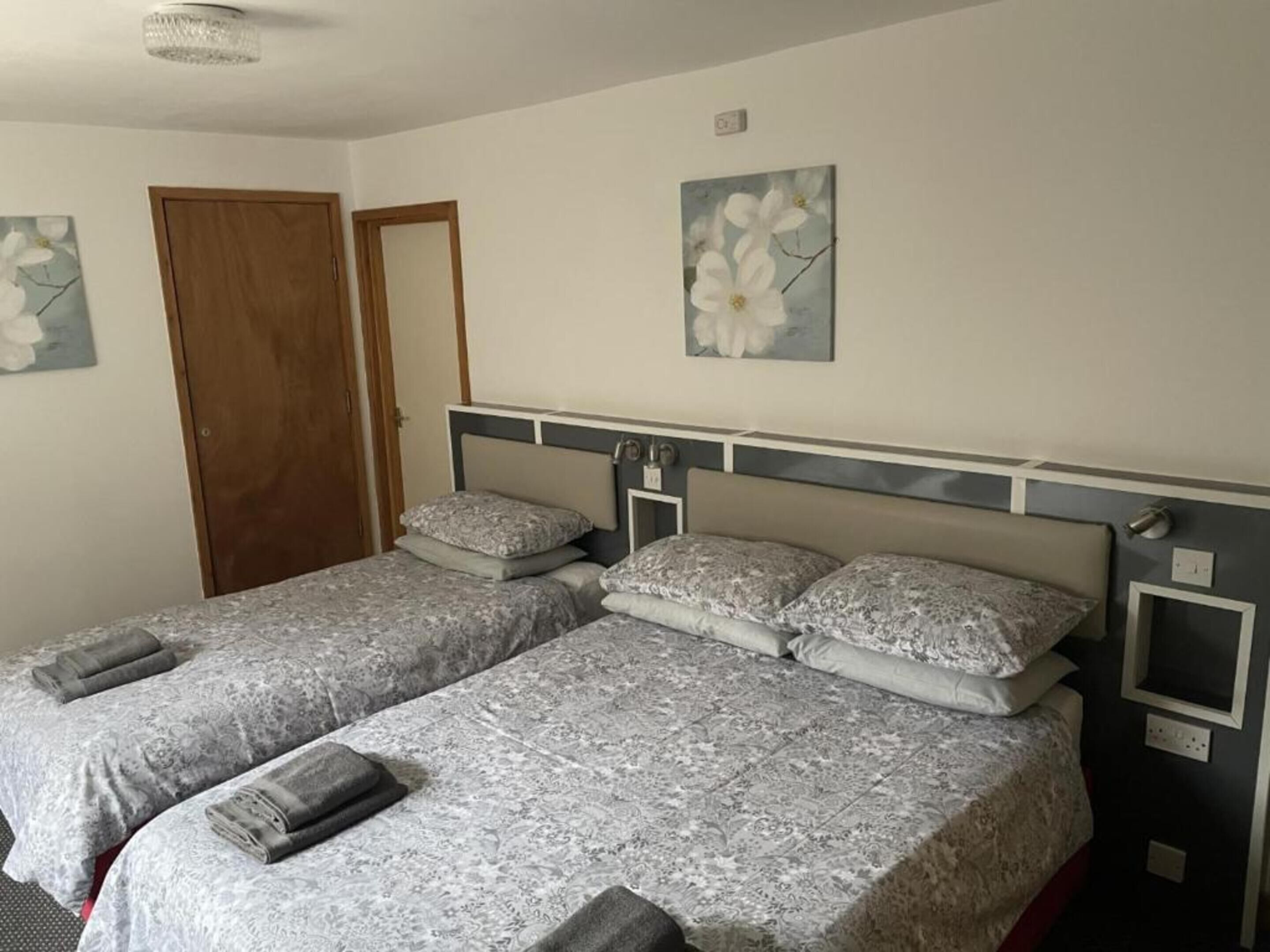 Ein Doppelzimmer mit zwei Betten, jeweils mit Kopfstütze, Kissen und gerollten Handtüchern.