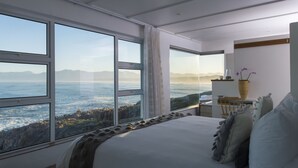 Une chambre avec un grand lit, un bureau et une vue sur l’oc éan.