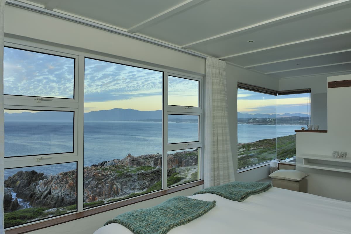 Un dormitorio con amplios ventanales que ofrecen vistas al mar.