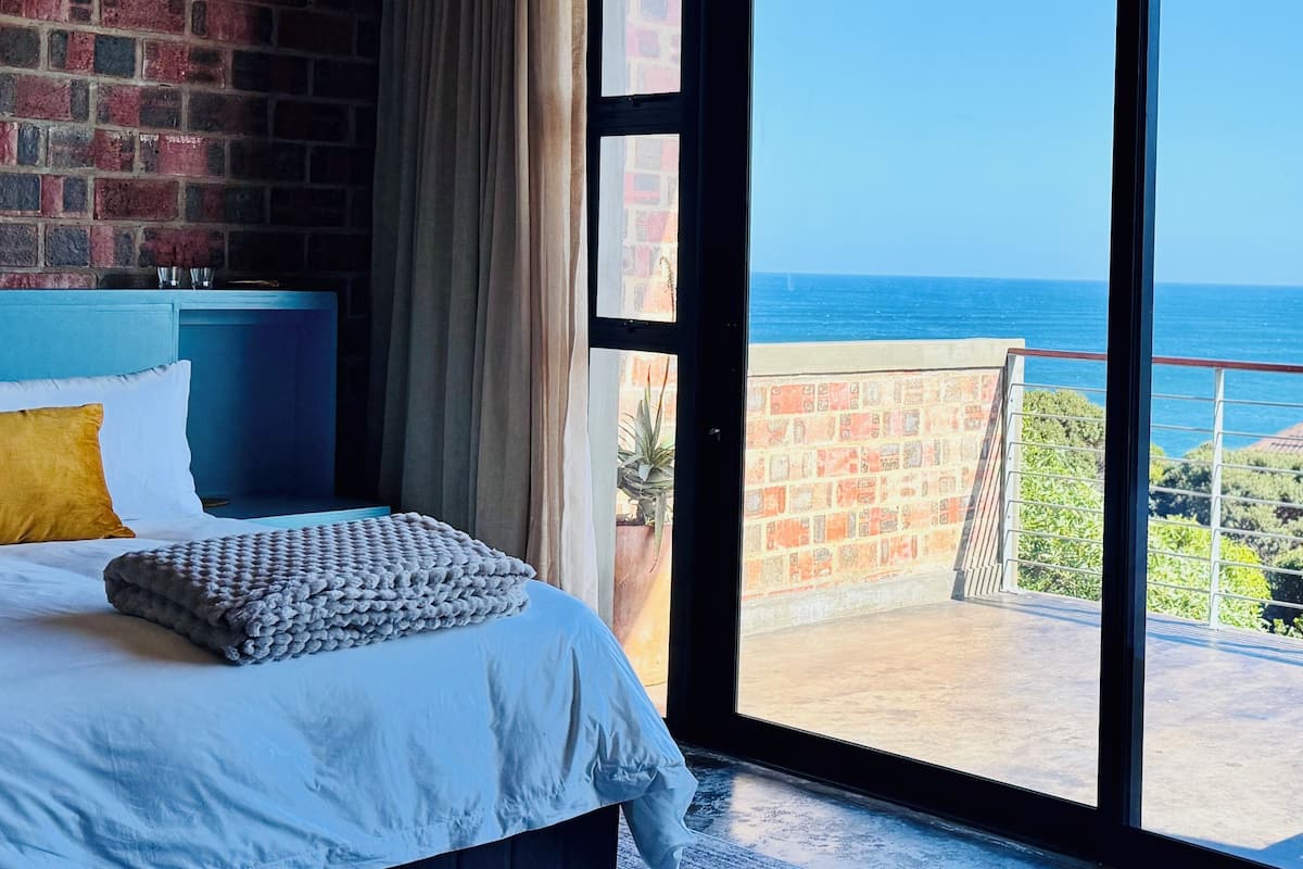 Un dormitorio con vista al mar, una pared de ladrillo y un balcón con barandilla.