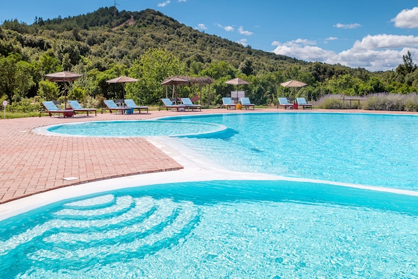Una piscina al aire libre, sombrillas, sillones reclinables de piscina
