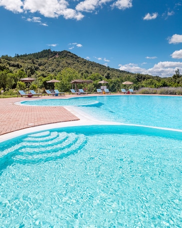 Una piscina al aire libre, sombrillas, sillones reclinables de piscina