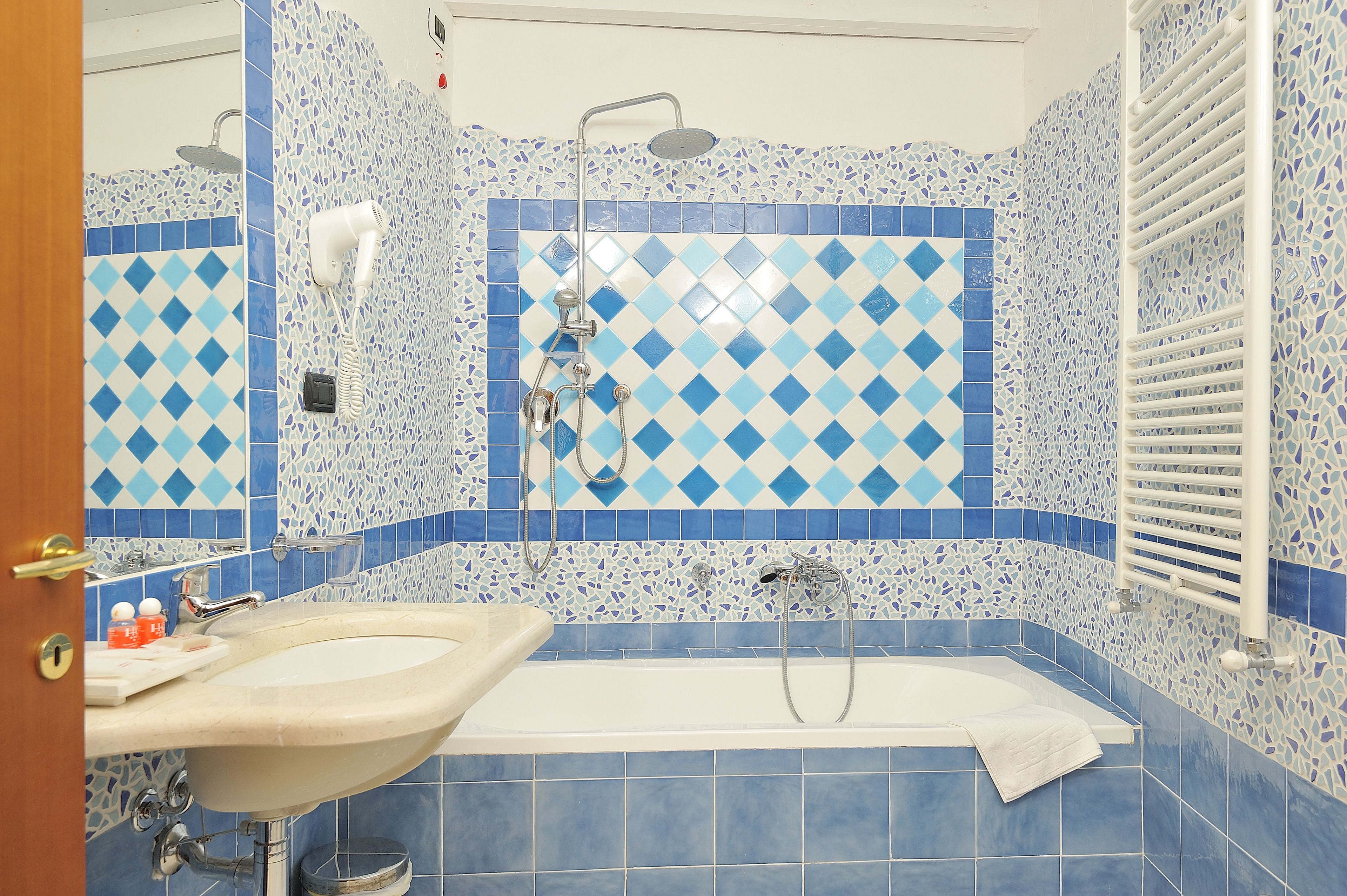 A bathroom with a sink, shower, and a towel rack.