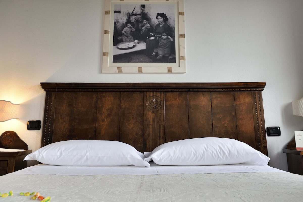 Ein Schlafzimmer mit einem hölzernen Kopfteil, weißer Bettwäsche und einem schwarzen und weißen Foto im Rahmen an der Wand.