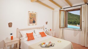 A bedroom with a bed, a nightstand, a tray with breakfast, and a window with a view of a green landscape.