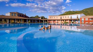 Relax by the serene pool surrounded by traditional Mediterranean-style buildings.