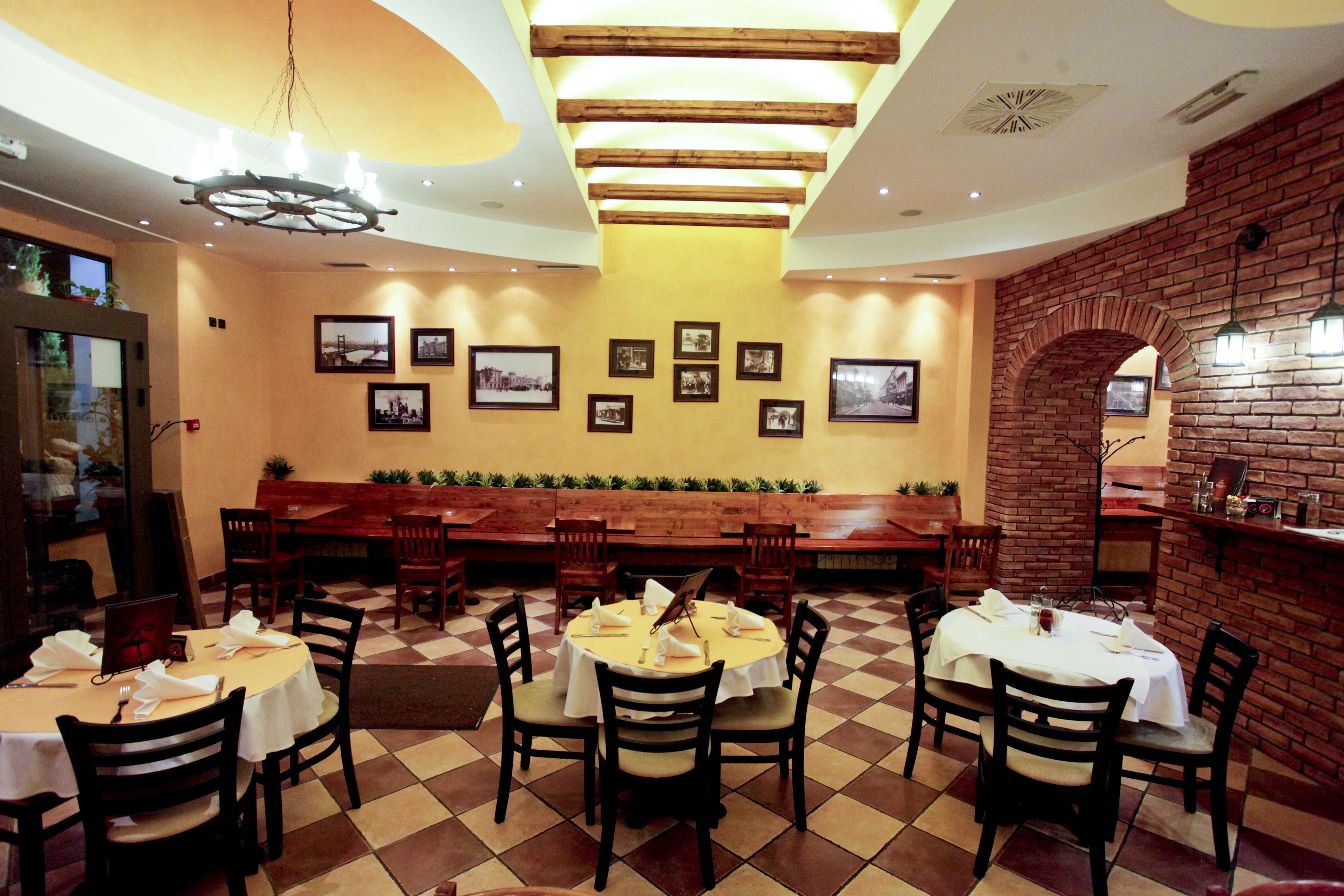 Un restaurant avec plusieurs tables et chaises, un mur en briques et des tableaux encadrés accrochés au mur.