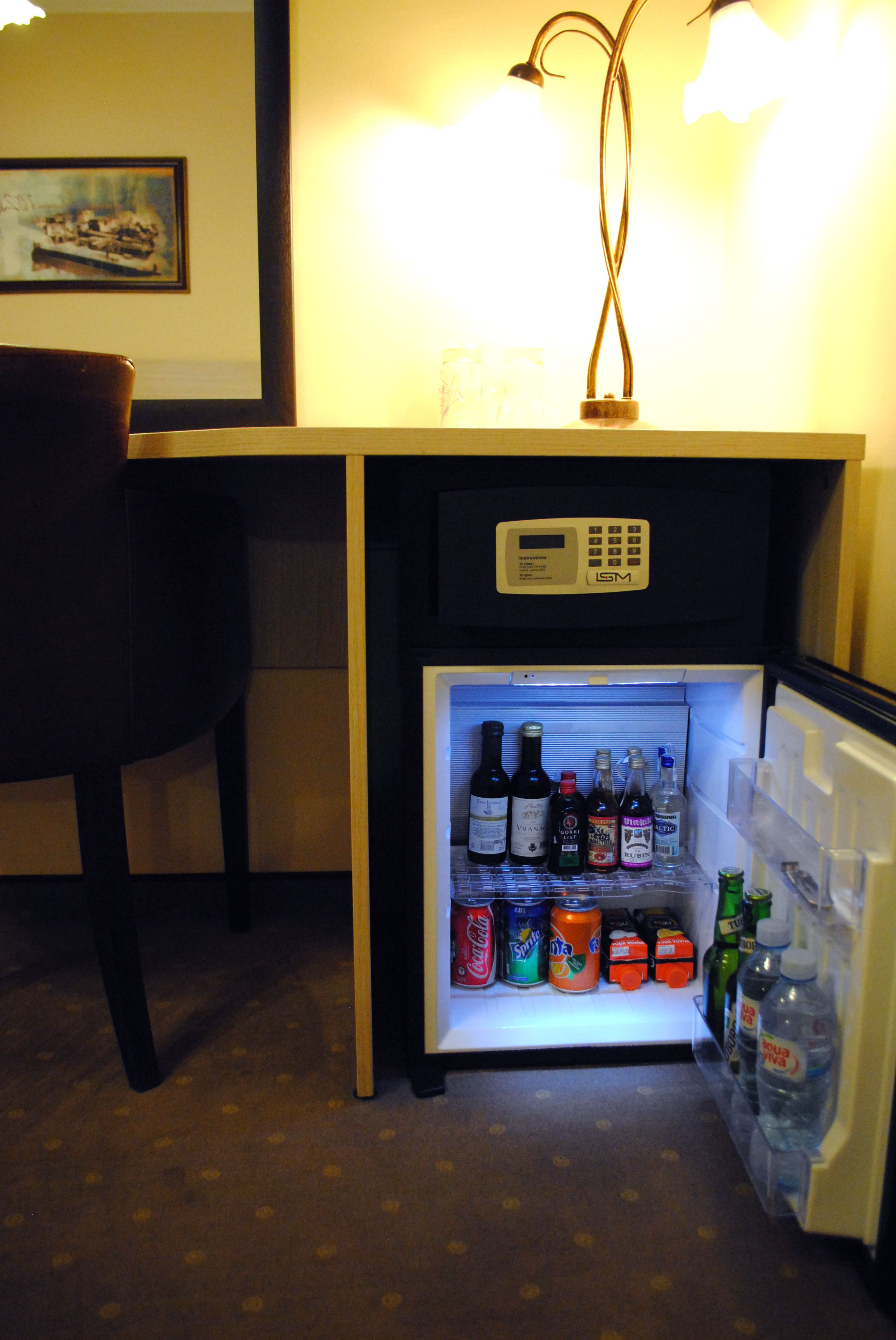 Un petit réfrigérateur doté d’un panneau de commande et contenant diverses boissons et conserves.