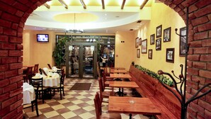 A restaurant with brick arches, wooden tables, and benches, featuring a checkered floor and a television on the wall. - Belgrade City Hotel (Belgrade)