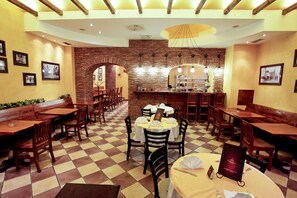 Ein Restaurant mit Schachbrettmuster-Boden, Holztischen und -stühlen, Ziegelwänden und einer Bar.