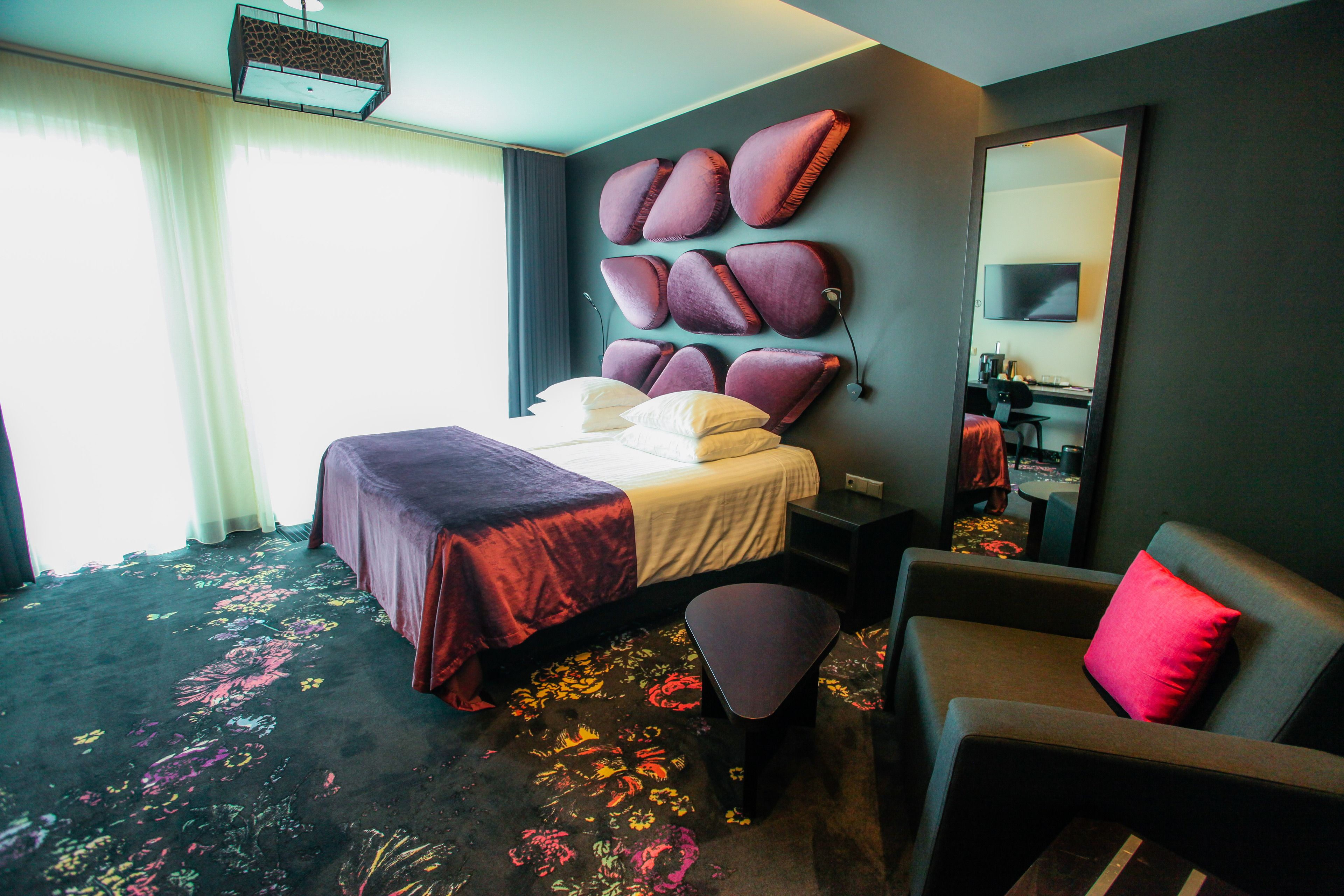 Ein Hotelzimmer mit Bett, Sitzgelegenheit, großem Spiegel und Fernseher.