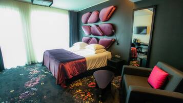 Ein Hotelzimmer mit Bett, Sitzgelegenheit, großem Spiegel und Fernseher.