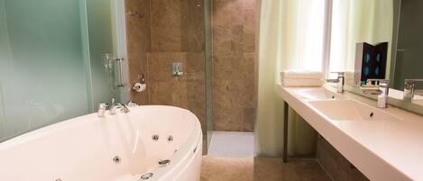 A modern bathroom with a large bathtub, a glass shower enclosure, and a vanity with a mirror and sink.