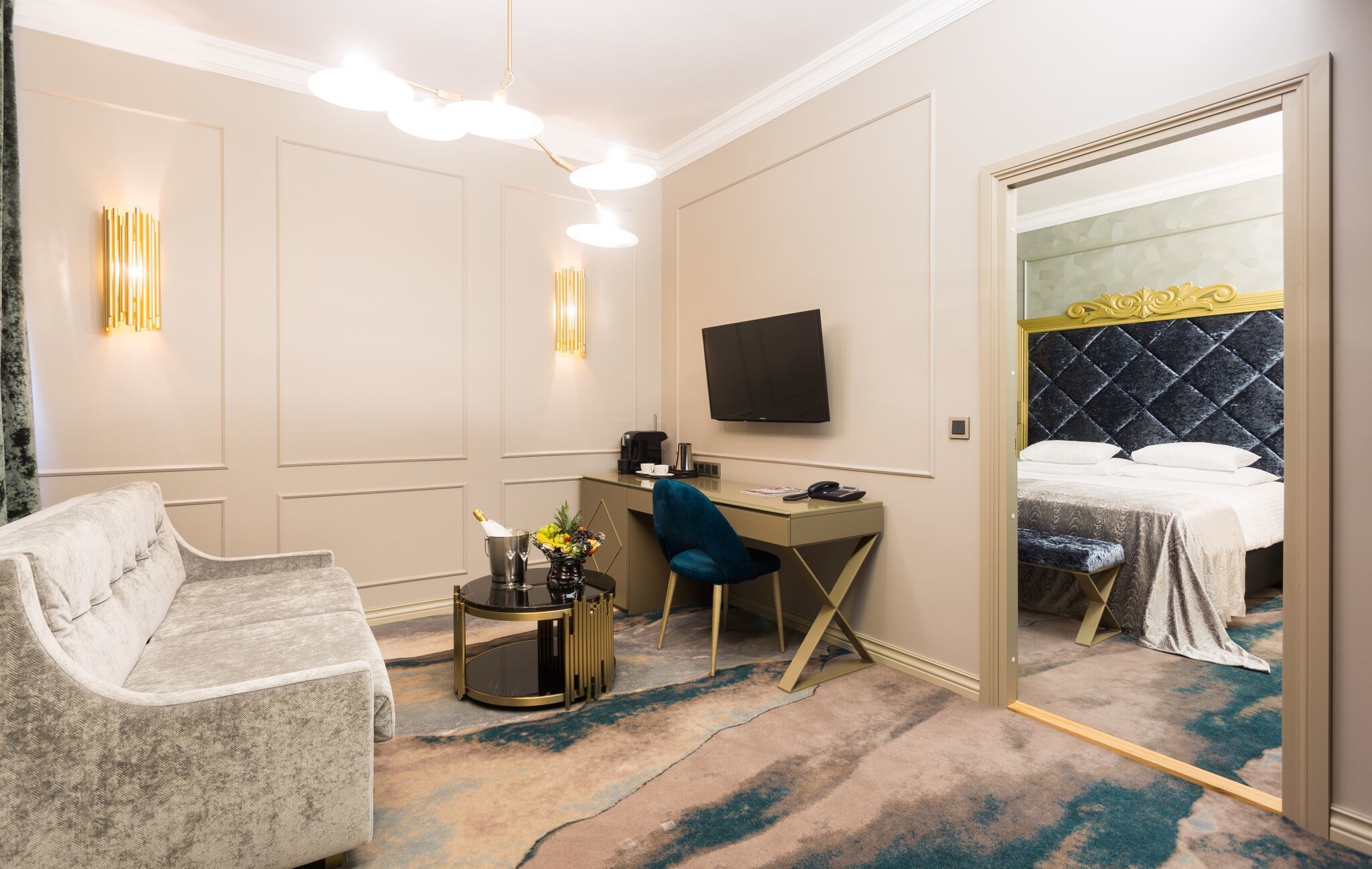 Habitación de hotel con cama, escritorio, silla, televisor y minibar.