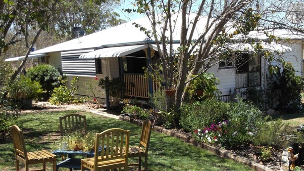 A backyard with a picnic table and chairs, surrounded by a garden with various plants and flowers. - Staple House Bed and Breakfast (Woolooga)