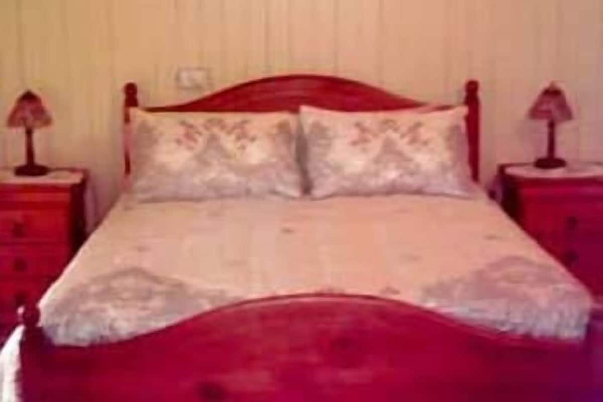 A bed with a wooden headboard, two bedside tables with lamps, and a plain wall.