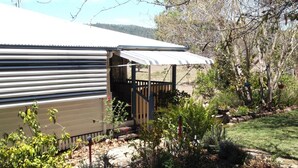 A residential property with a covered patio, a fenced garden area, and a variety of plants. - Staple House Bed and Breakfast (Woolooga)