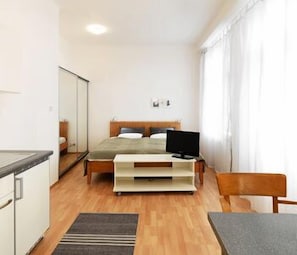 Una habitación de hotel pequeña con cama, televisión, una mesita y una silla.