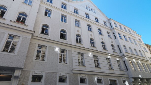 A multi-story building with a classical architectural style, featuring symmetrical windows and decorative moldings.