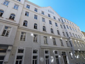 Ένα πολυώροφο κτίριο με κλασικό αρχιτεκτονικό στυλ, που διακρίνεται για τα συμμετρικά παράθυρα και τα διακοσμητικά γείσα.