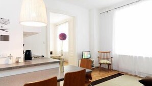 A modern kitchen with a dining area, a large window, and a wooden floor.
