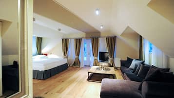 A modern hotel room with a bed, a sofa, a TV, and a dining table.