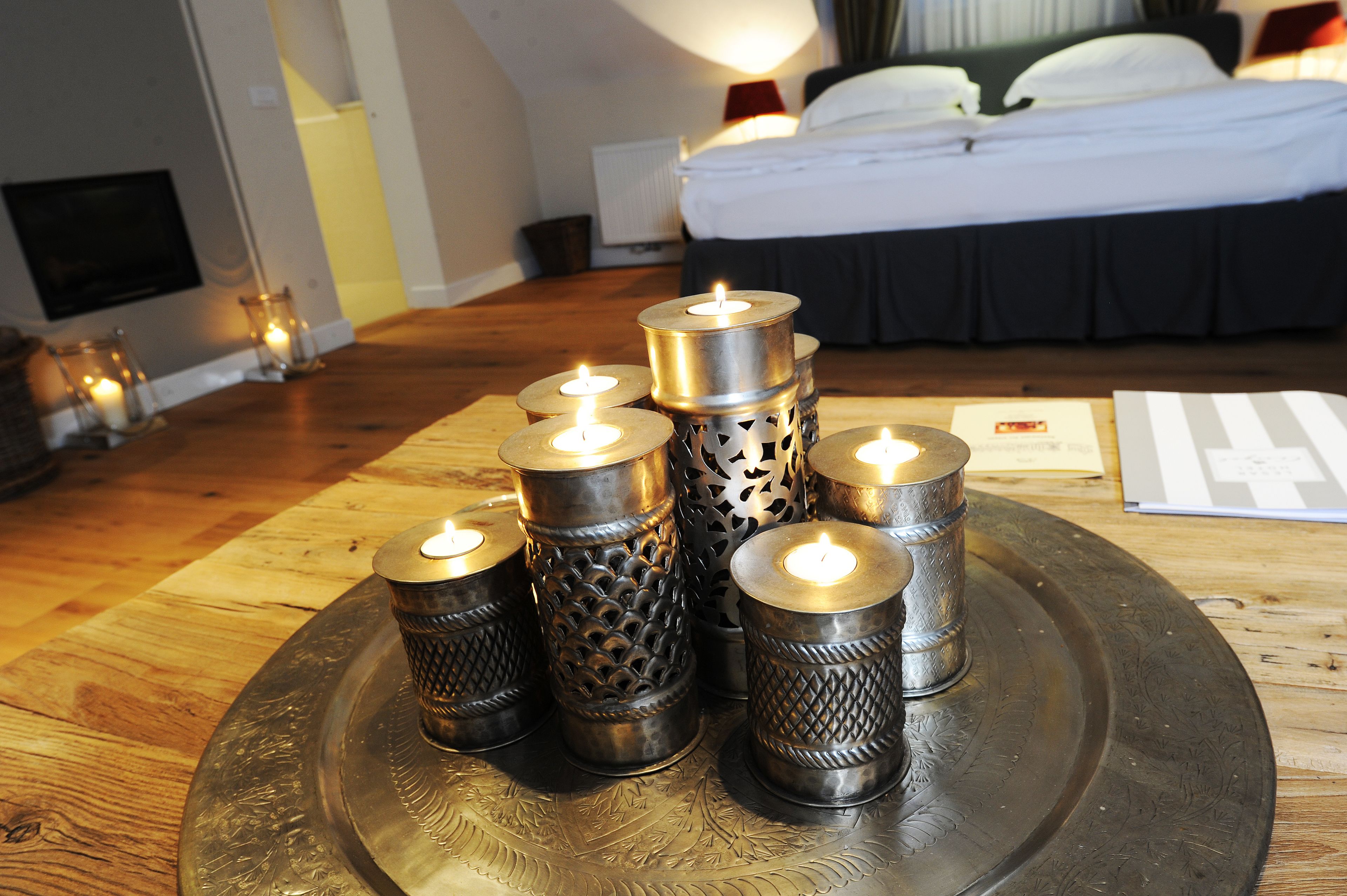 Una habitación con una cama, una mesita de noche con velas y un televisor en la pared.