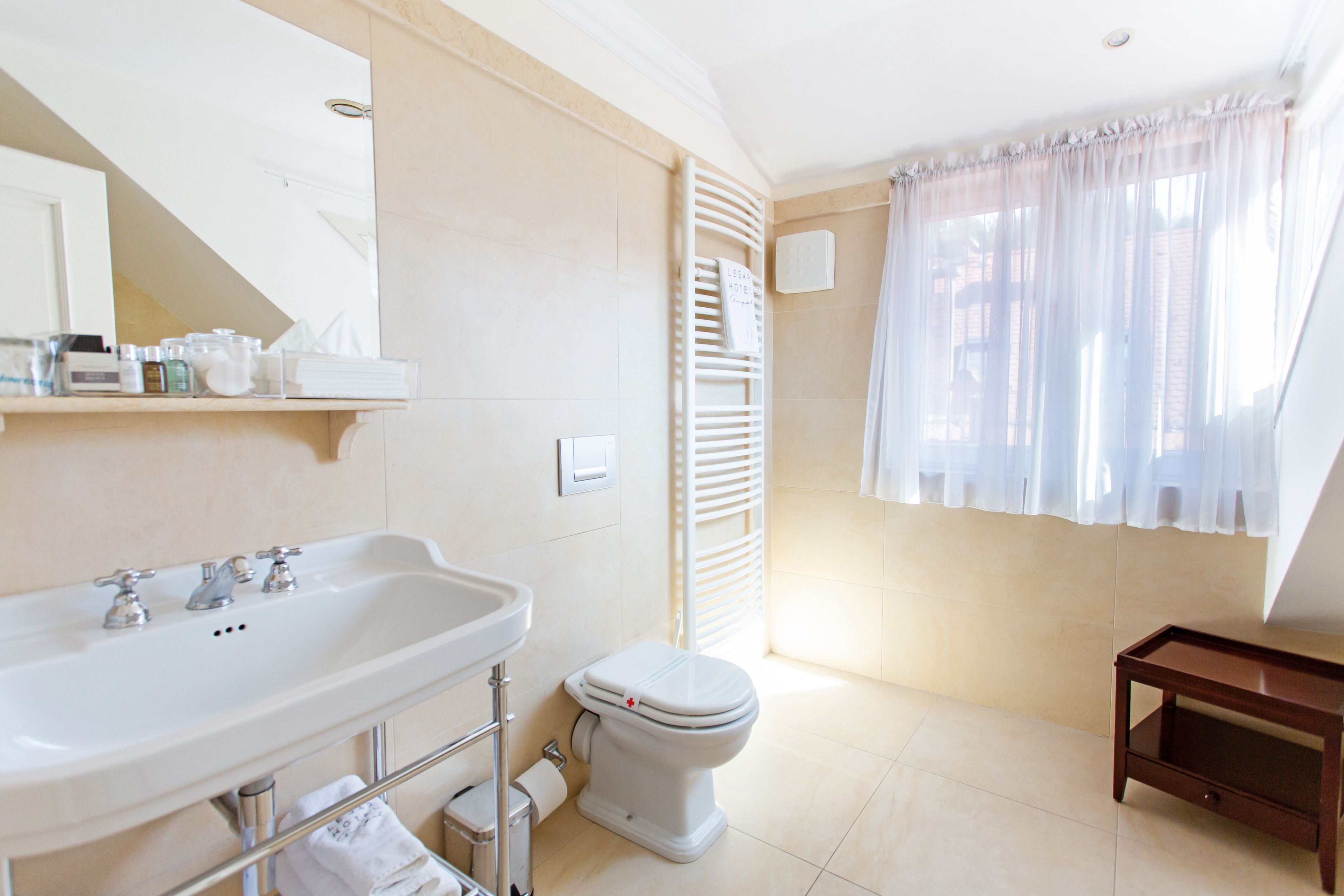 A bathroom with a white sink, toilet, and a small wooden side table.