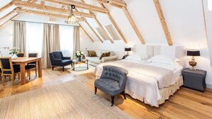 A spacious loft bedroom with a high ceiling, wooden beams, a large bed, a desk, and a chair. - Lesar Hotel Angel (Ljubljana)