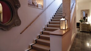 A staircase with a wooden handrail and a lantern on the landing. - Lesar Hotel Angel (Ljubljana)