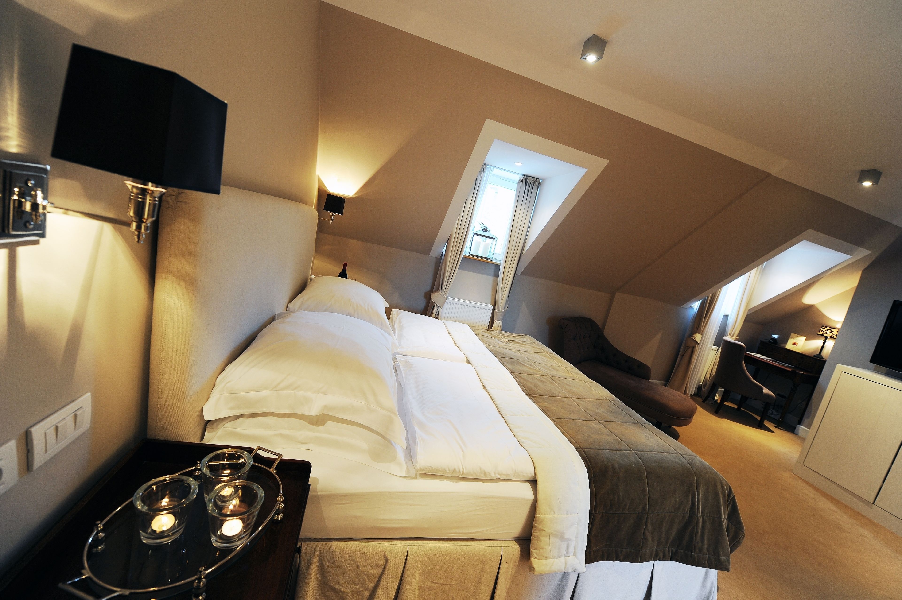 A bedroom with a bed, bedside table, and a desk area with a chair.