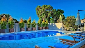 A swimming pool with lounge chairs and potted plants. - Grande Kloof Boutique Hotel (Cape Town)