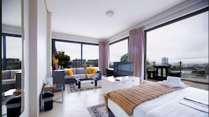A modern hotel room with a large bed, a sofa, a TV, and a balcony with a city view. - Grande Kloof Boutique Hotel (Cape Town)