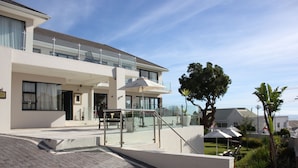 A modern two-story house with a balcony, outdoor seating, and a well-maintained garden. - Grande Kloof Boutique Hotel (Cape Town)
