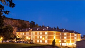 A multi-story hotel with a brick facade, multiple windows, and a parking lot with steps leading to the entrance.