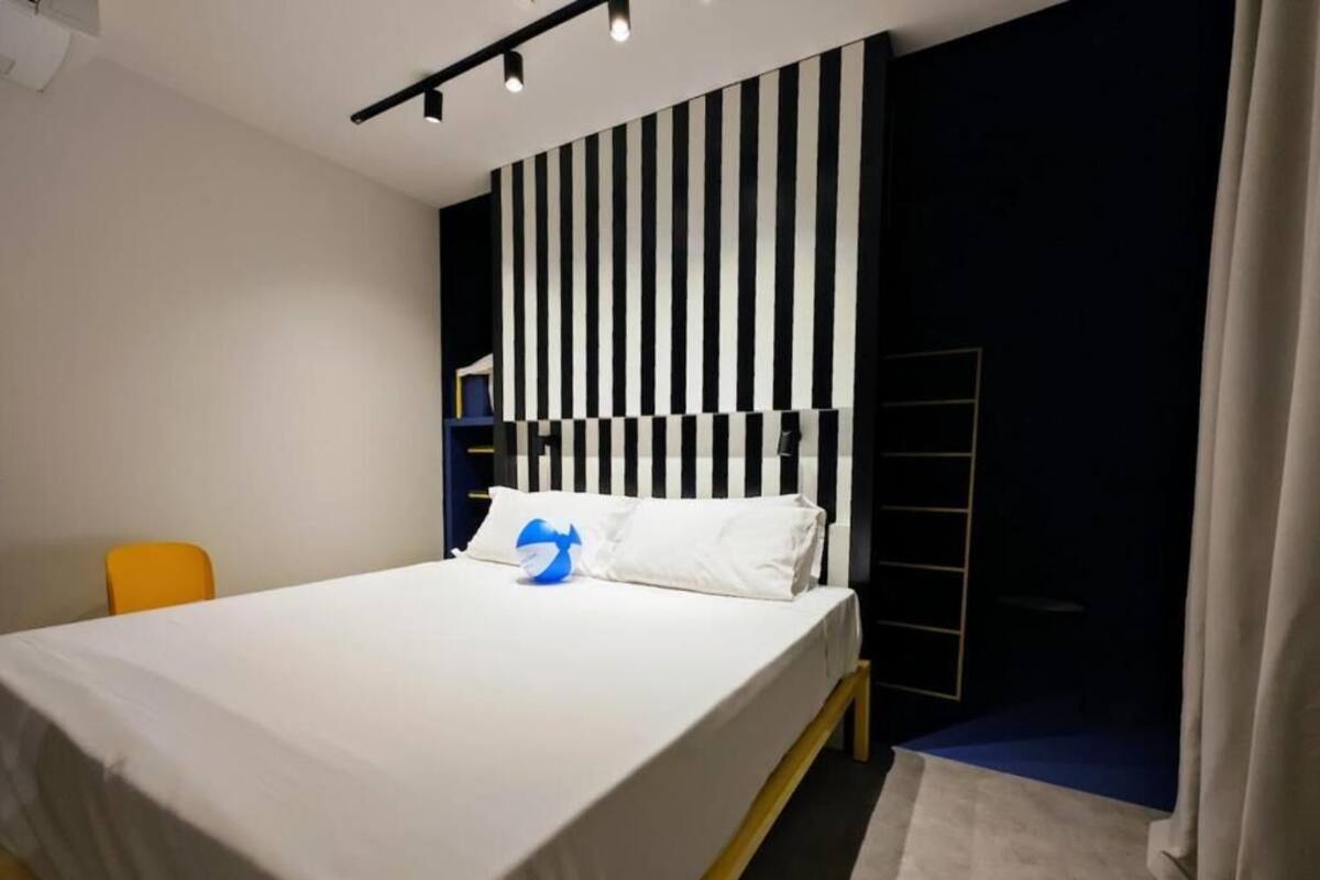 Une chambre moderne avec un lit, une chaise, une table de chevet et un mur à rayures.