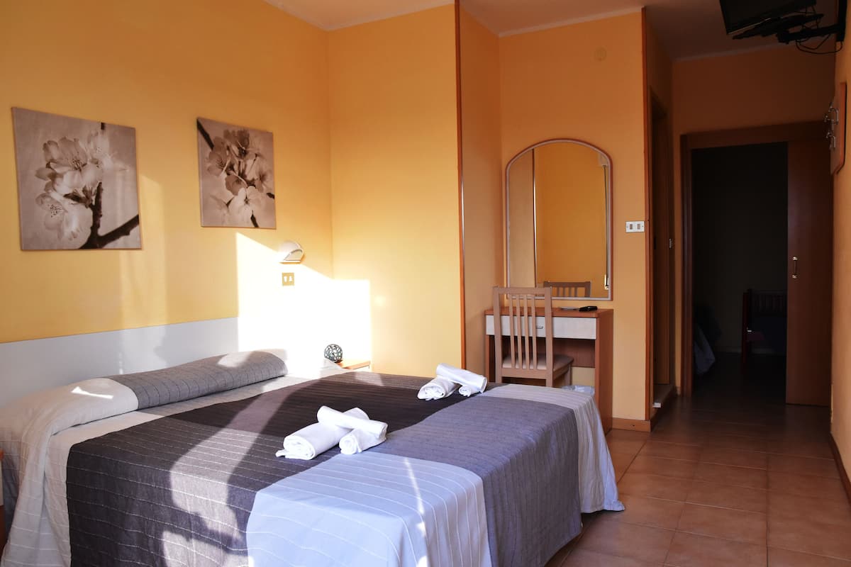 Une chambre d’hôtel avec deux lits, une table de chevet, un miroir et des œuvres d’art accrochées au mur.