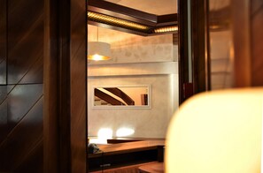 A modern bathroom with a large mirror, wooden paneling, and a bench.