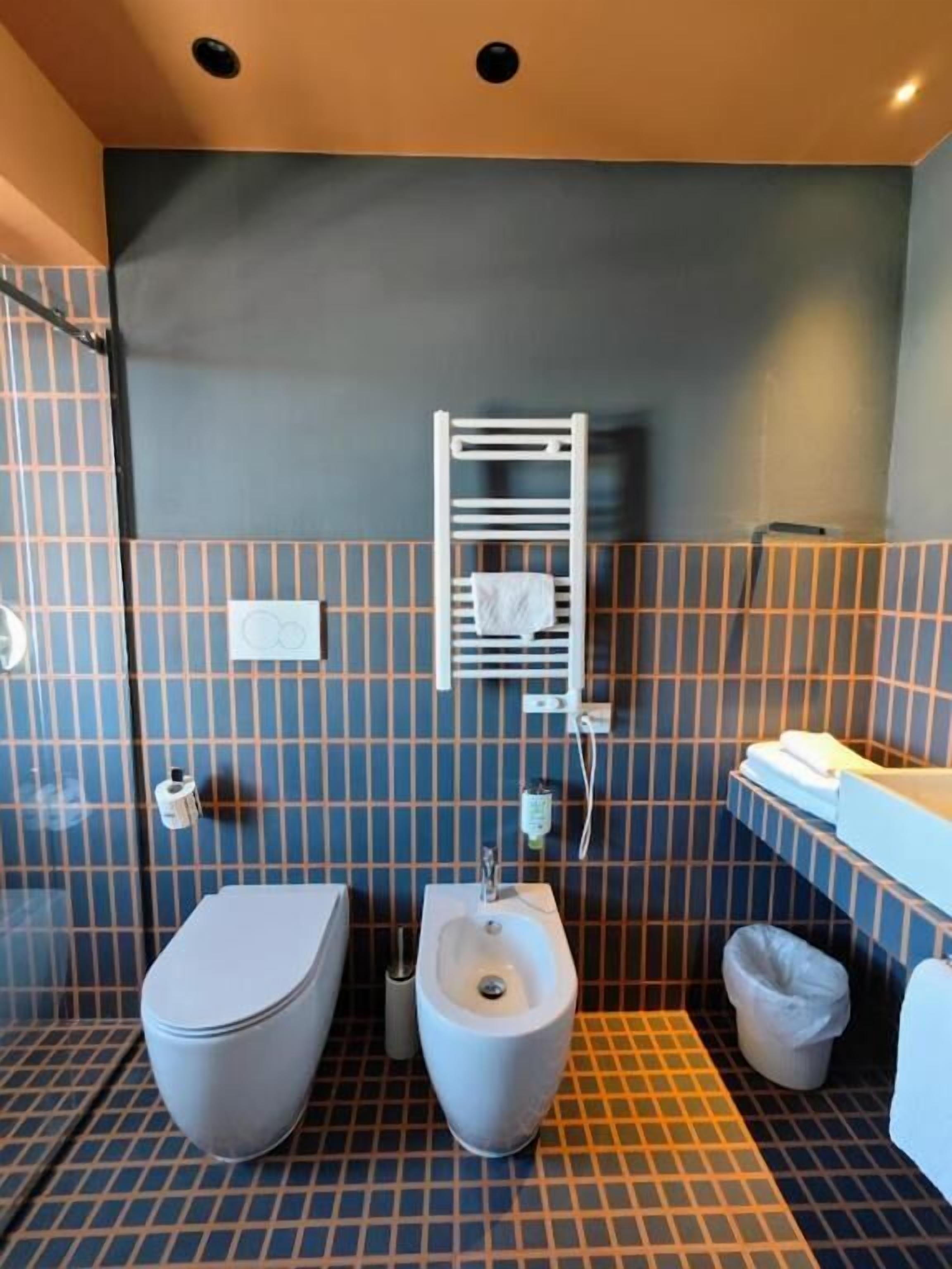 A bathroom with a toilet, bidet, and a towel rack on the wall.