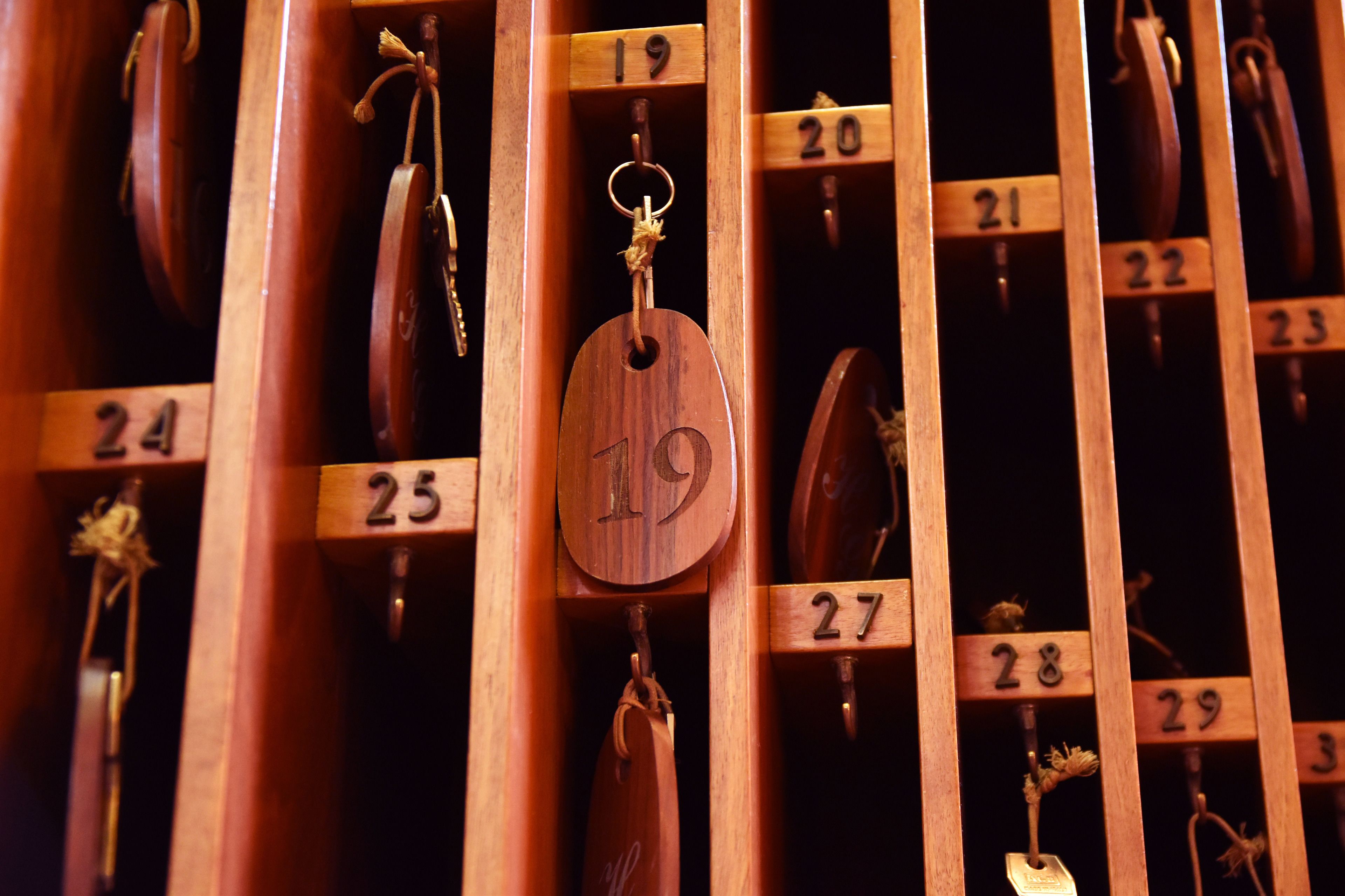 A wooden wall with numbered compartments, each holding a key.