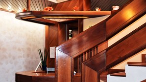 A wooden staircase with a built-in heater, a reception desk, and a potted plant. - Hotel Graziella (Bellaria-Igea Marina)
