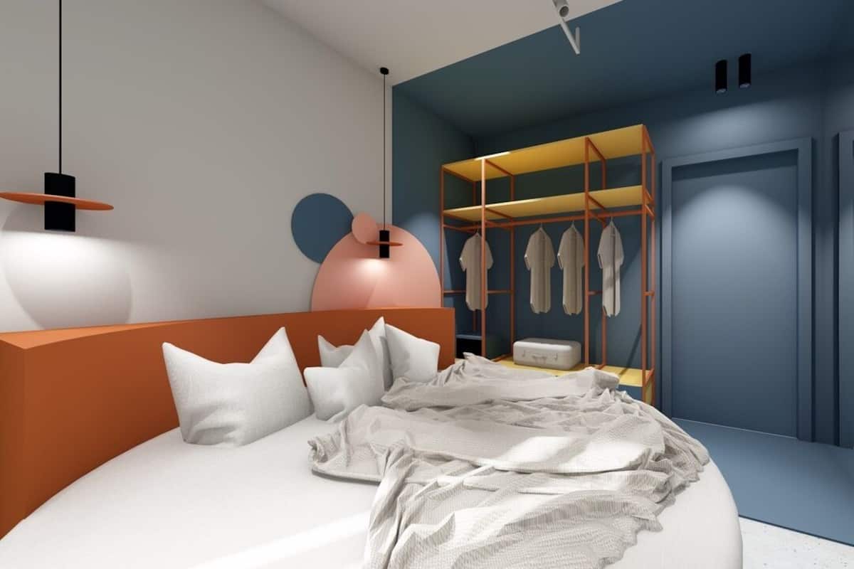 Une chambre à coucher moderne avec un lit aux lignes courbes, une armoire où sont suspendus les vêtements et une table de chevet.