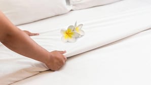 A bed with white linens and a single white and yellow flower placed on the bed. - Flipper Hotel Amsterdam (Amsterdam)