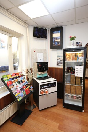 A reception area with a digital display, a refrigerator stocked with snacks, and a window with a view of the outside. - Flipper Hotel Amsterdam (Amsterdam)