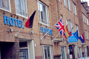 Un hotel llamado "HOTEL FLIPPER" con varias banderas, incluyendo la bandera del Reino Unido, y una fachada de ladrillo.