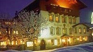 Un edificio de varios pisos con un techo destacado y numerosas ventanas, rodeado de nieve.