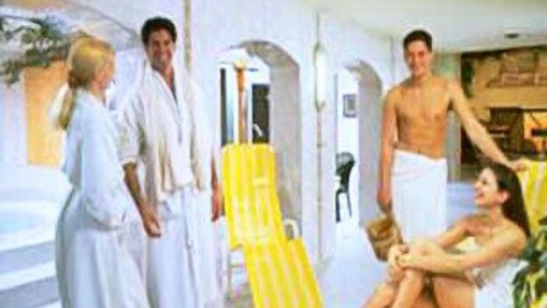 Una habitación con una cama, un sillón amarillo y una persona sentada en él.